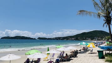 Nära stranden, vit sandstrand, solstolar och parasoller