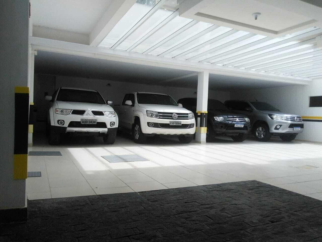 Un parking couvert où trois voitures sont garées à la suite.