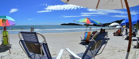 A beach with sun loungers and umbrellas, a clear sky, and the ocean in the background.