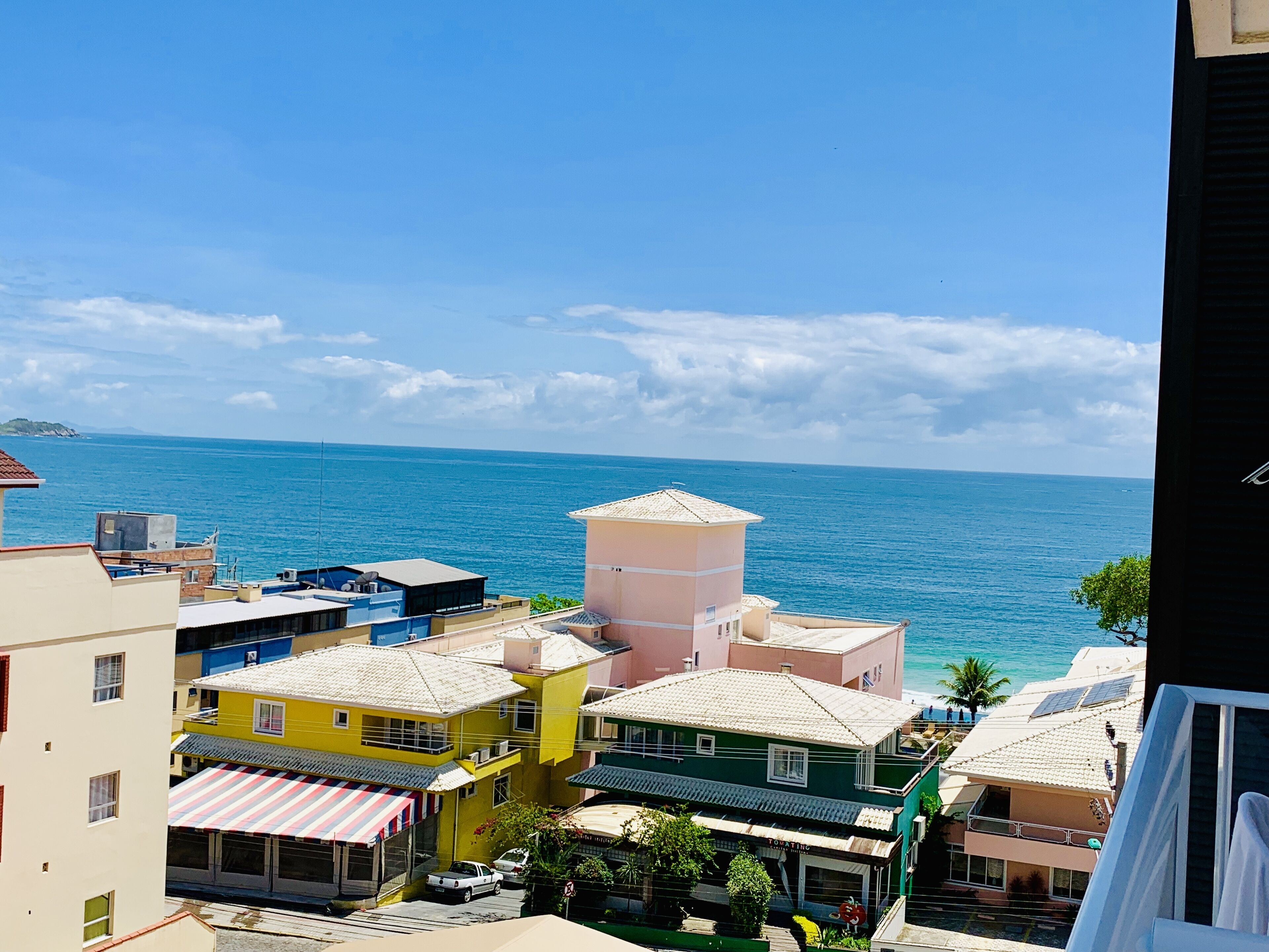 A coastal town with colorful buildings, a clear blue sky, and the sea in the background.