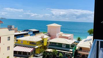 A coastal town with colorful buildings, a clear blue sky, and the sea in the background.