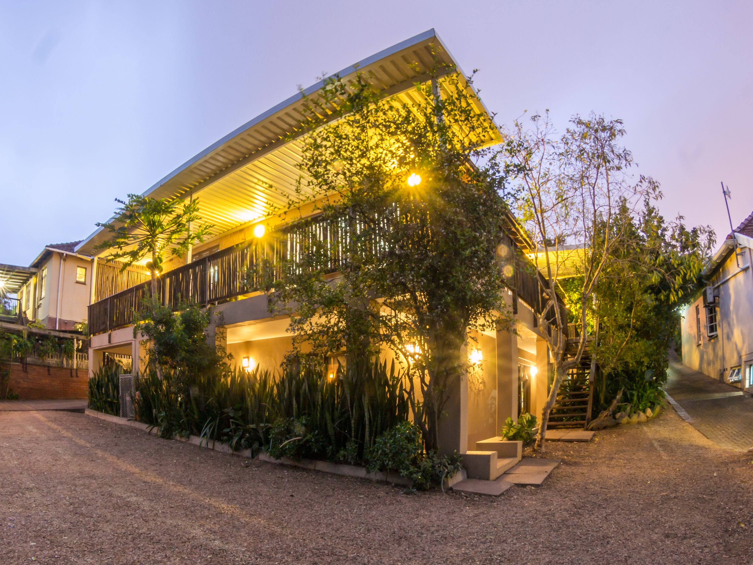 A modern house with a covered porch, a staircase, and a well-maintained garden.