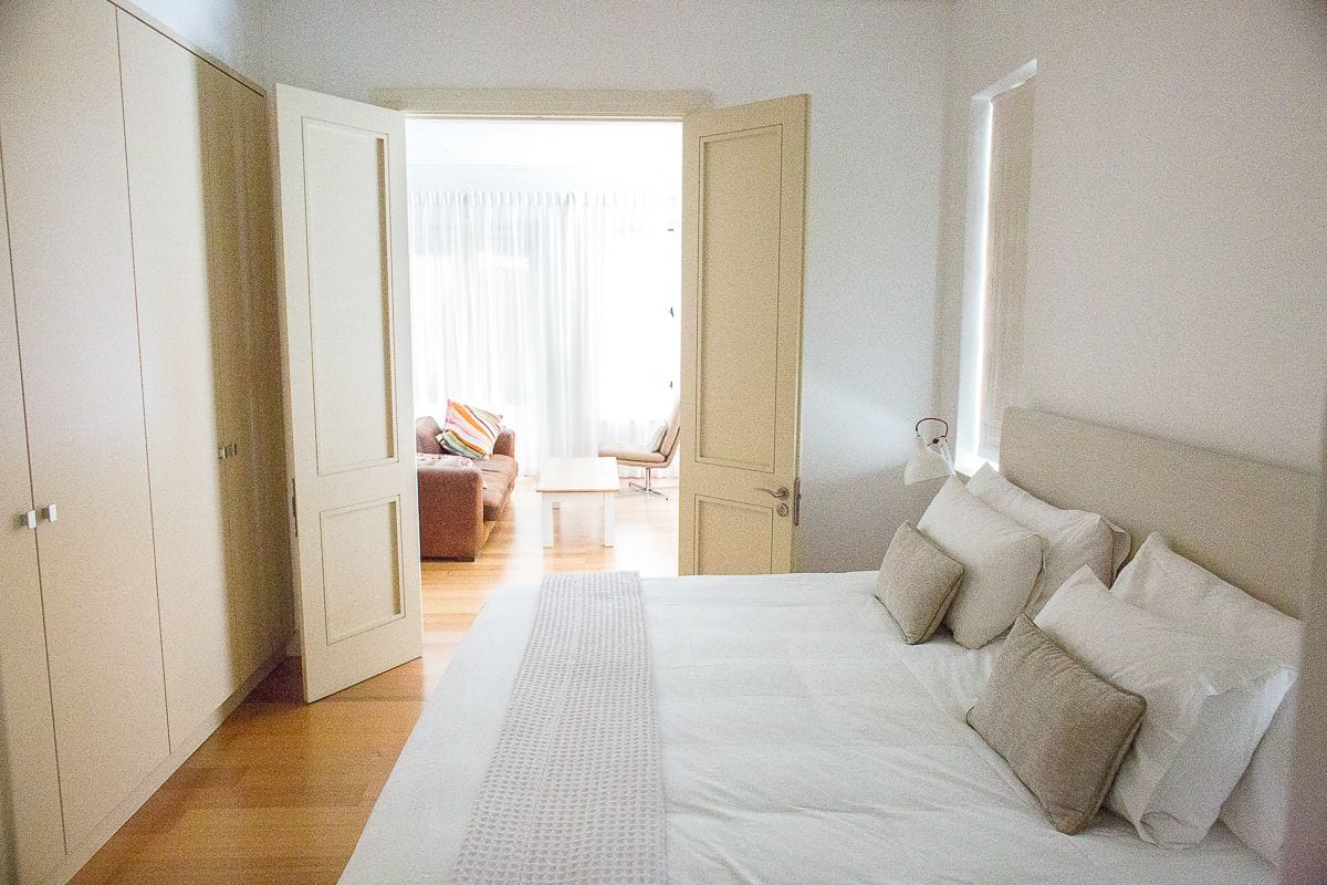 Een slaapkamer met een groot bed, een kledingkast en een deur naar een balkon.