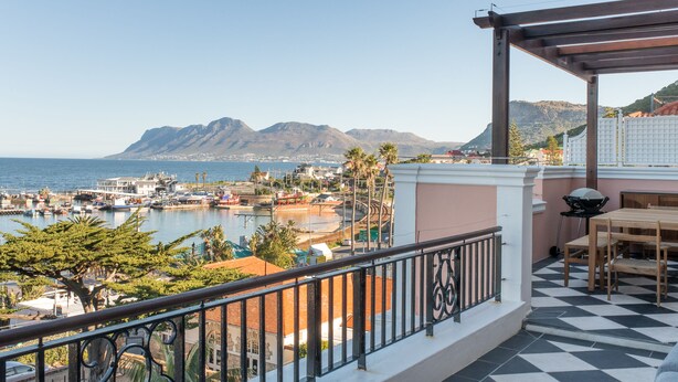 Een balkon met uitzicht op een jachthaven, boten en bergen.