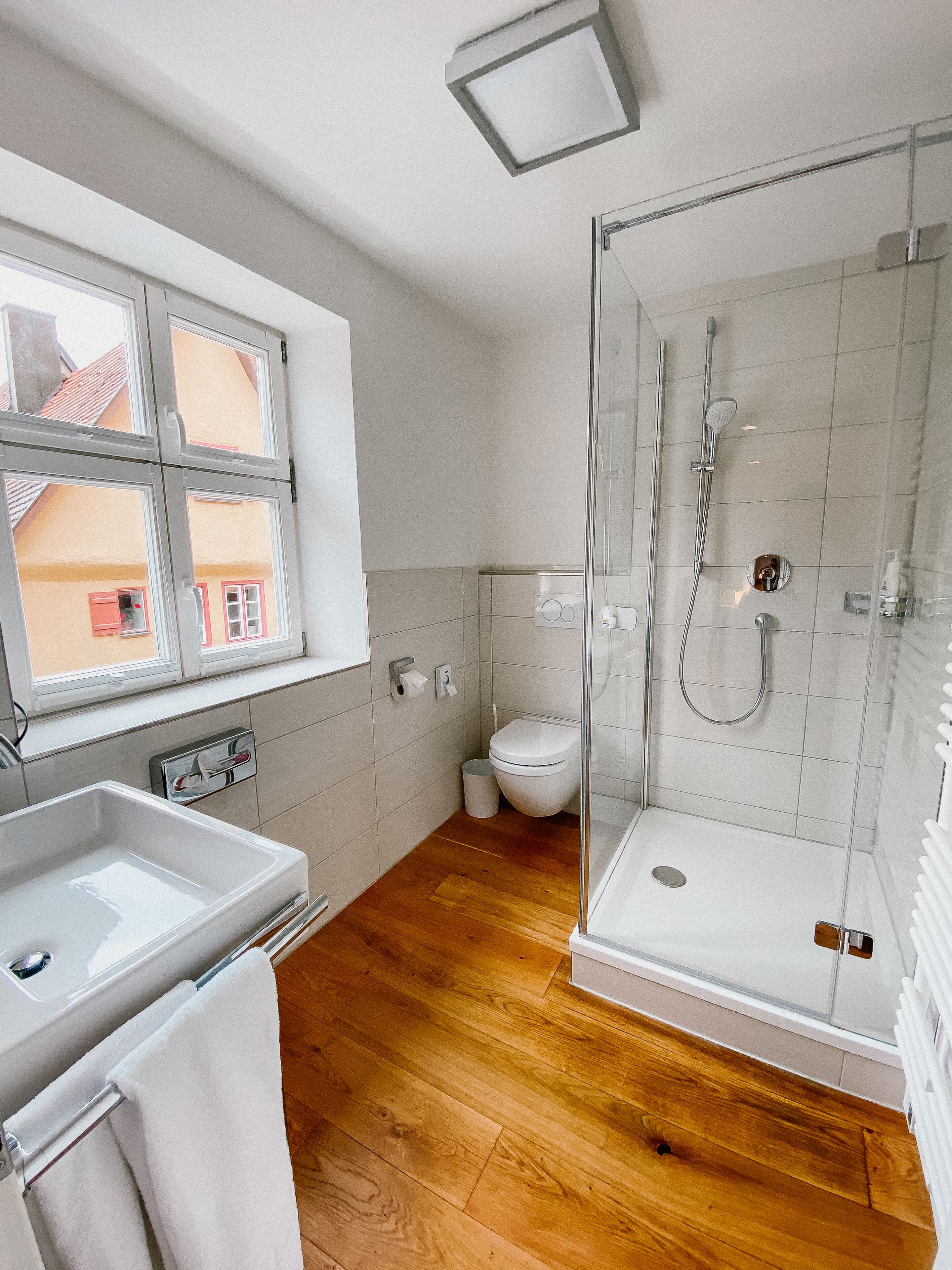 A modern bathroom with a glass-enclosed shower, a white sink, and a toilet.