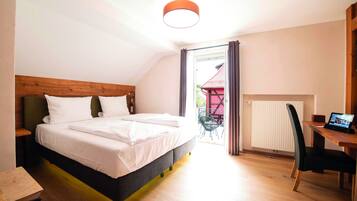 A bedroom with a bed, a wooden headboard, a desk with a chair, and a view of the outside.