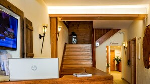 A reception desk with a wooden design, a laptop, and a staircase leading to upper floors.