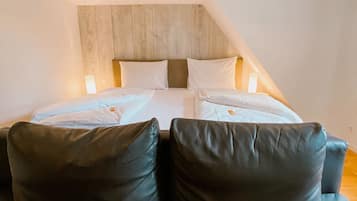 Un dormitorio con cama, dos almohadas, cabecera de madera y un sofá.