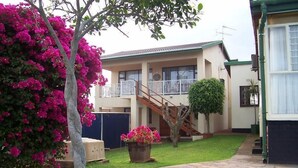 A two-story building with a balcony, a swimming pool, and a well-maintained lawn. - Birdcage B and B (Kingsburgh)