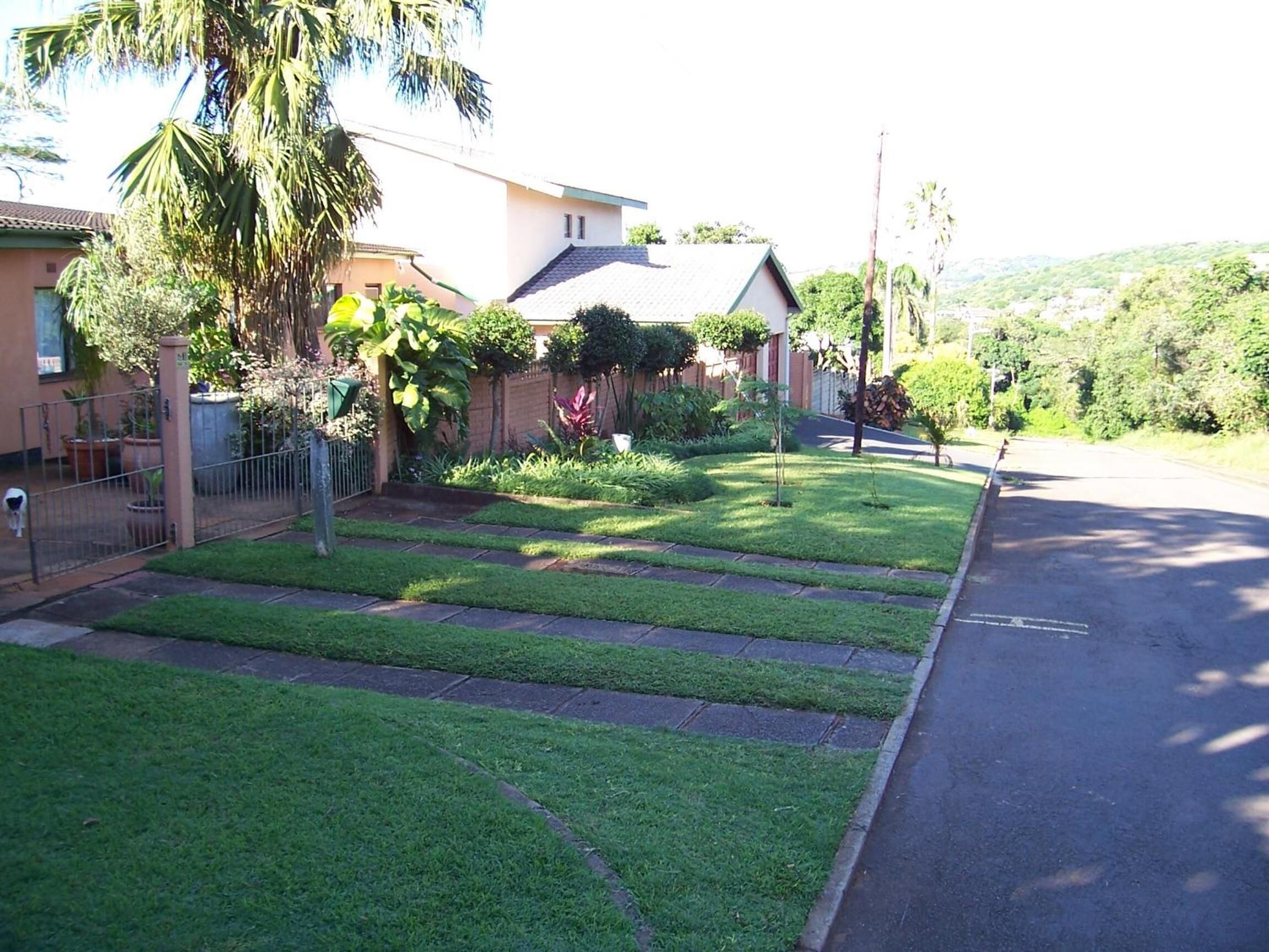 Une rue résidentielle bordée de maisons, avec une pelouse bien entretenue et un trottoir.
