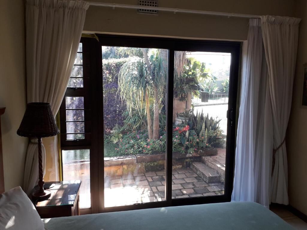 Una stanza con un letto, un comodino, una lampada e una porta a vetri scorrevoli che dà su un giardino.