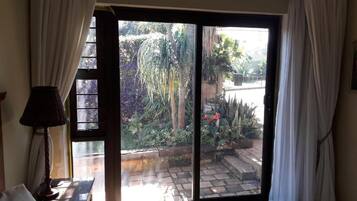 Una stanza con un letto, un comodino, una lampada e una porta a vetri scorrevoli che dà su un giardino.