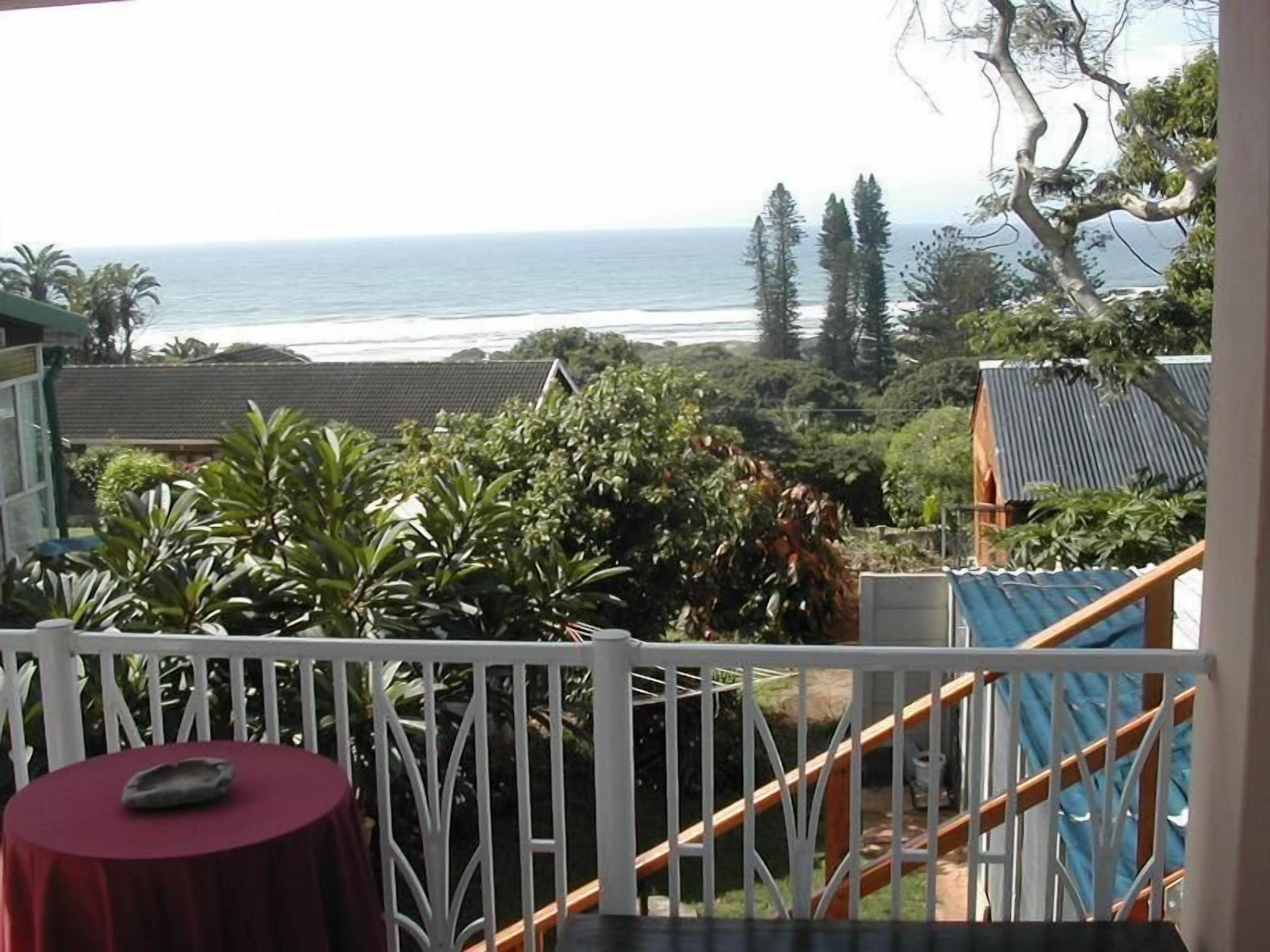 Uma varanda com vista para o oceano, uma mesa pequena e um corrimão.