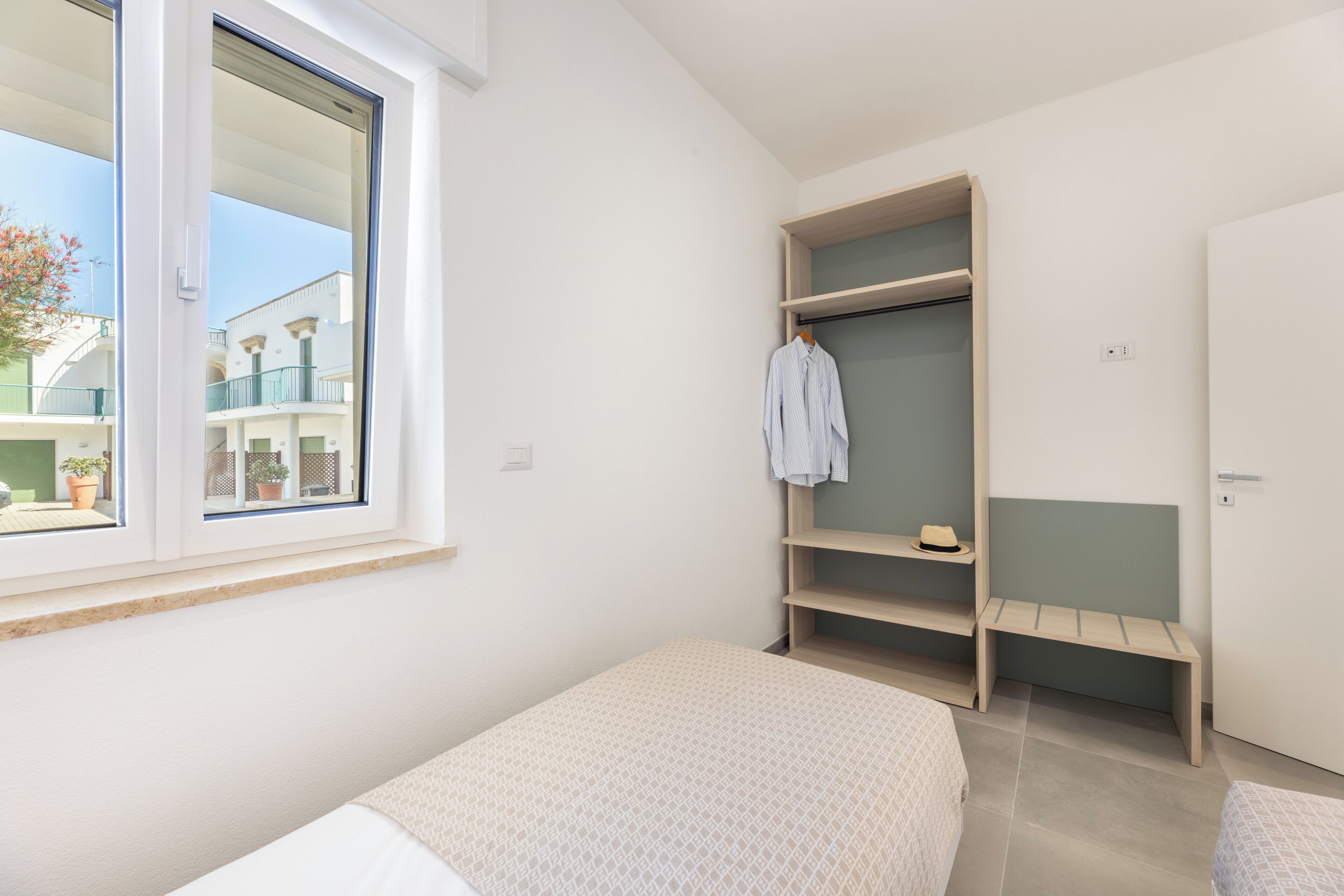 A bedroom with a window, a wardrobe, and a bed.