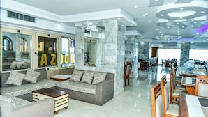 A modern hotel lobby with a sofa, chairs, and a dining area. - Regency Hotel Alexandria (Alexandria)