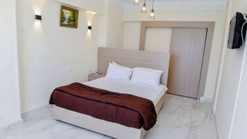 A modern bedroom with a large bed, a nightstand, a wall-mounted light, and a door.