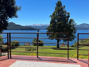 A terrace with a metal railing overlooking a lake, a bench, and a tree. - Costa Brava Apart Hotel (San Carlos de Bariloche)
