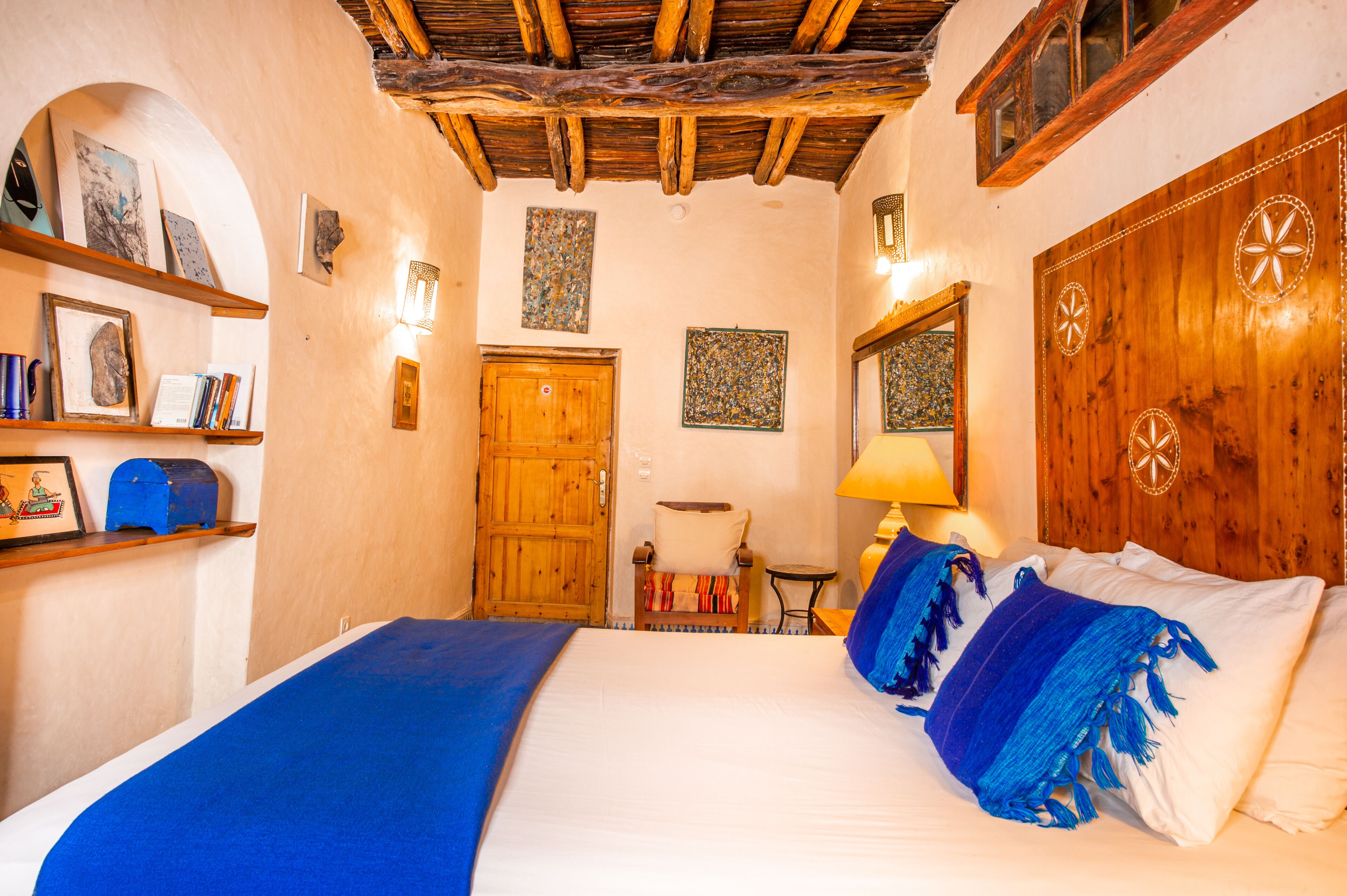 A room with a bed, wooden headboard, and a wooden door.