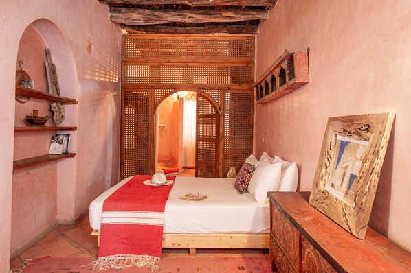 A cozy bedroom with a wooden bed, a red throw blanket, and a wooden headboard. - Dar Cherazade & Spa (Essaouira)