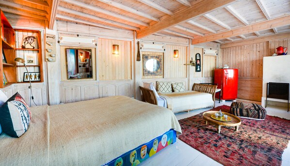 A cozy room with a bed, a sofa, a red refrigerator, and a wooden ceiling. - Dar Cherazade & Spa (Essaouira)