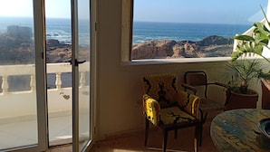 A room with a view of the ocean, a balcony, a chair, and a table. - Dar Cherazade & Spa (Essaouira)
