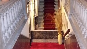 A grand staircase with a red carpet leading up to a landing, flanked by white balustrades. - Hotel Uruguay (Montevideo)