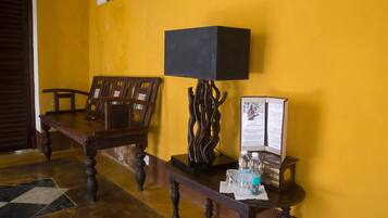 Una habitación con un banco de madera, una mesa con una lámpara negra y una pequeña vitrina con material informativo.
