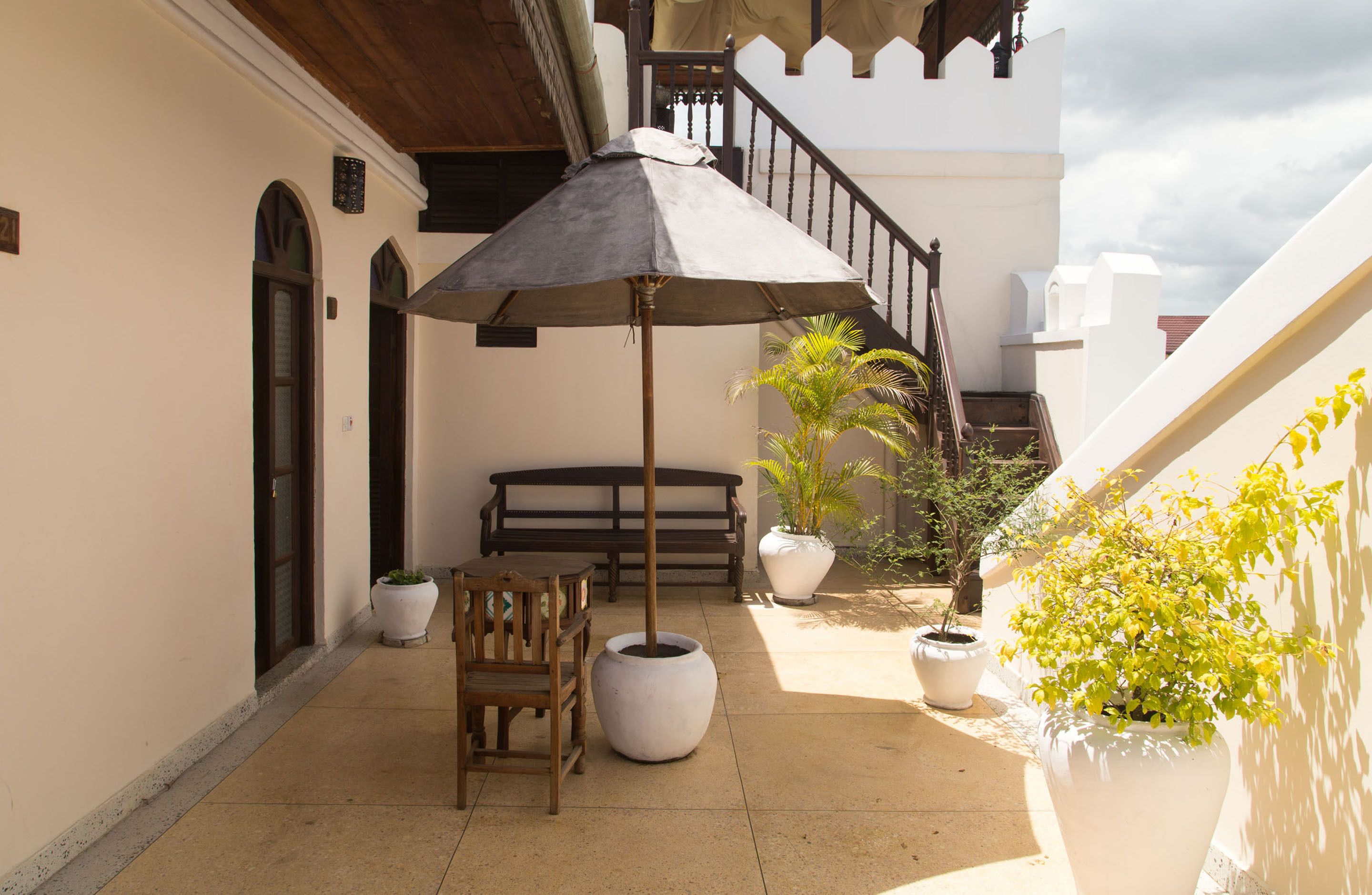 A covered outdoor seating area with a bench, a table, and a large umbrella.