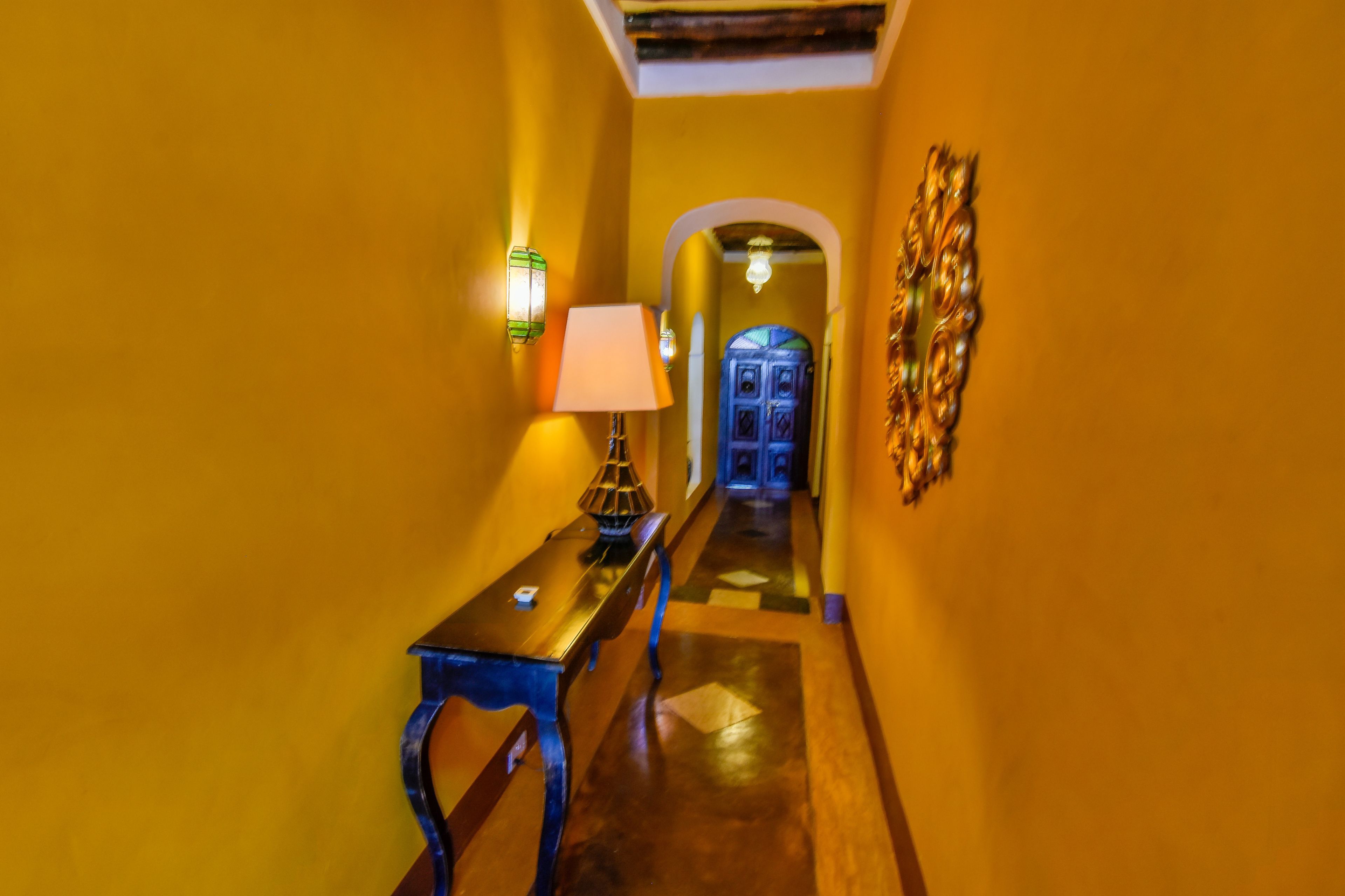 A hallway with a wooden bench, a lamp, and a wall-mounted light fixture.