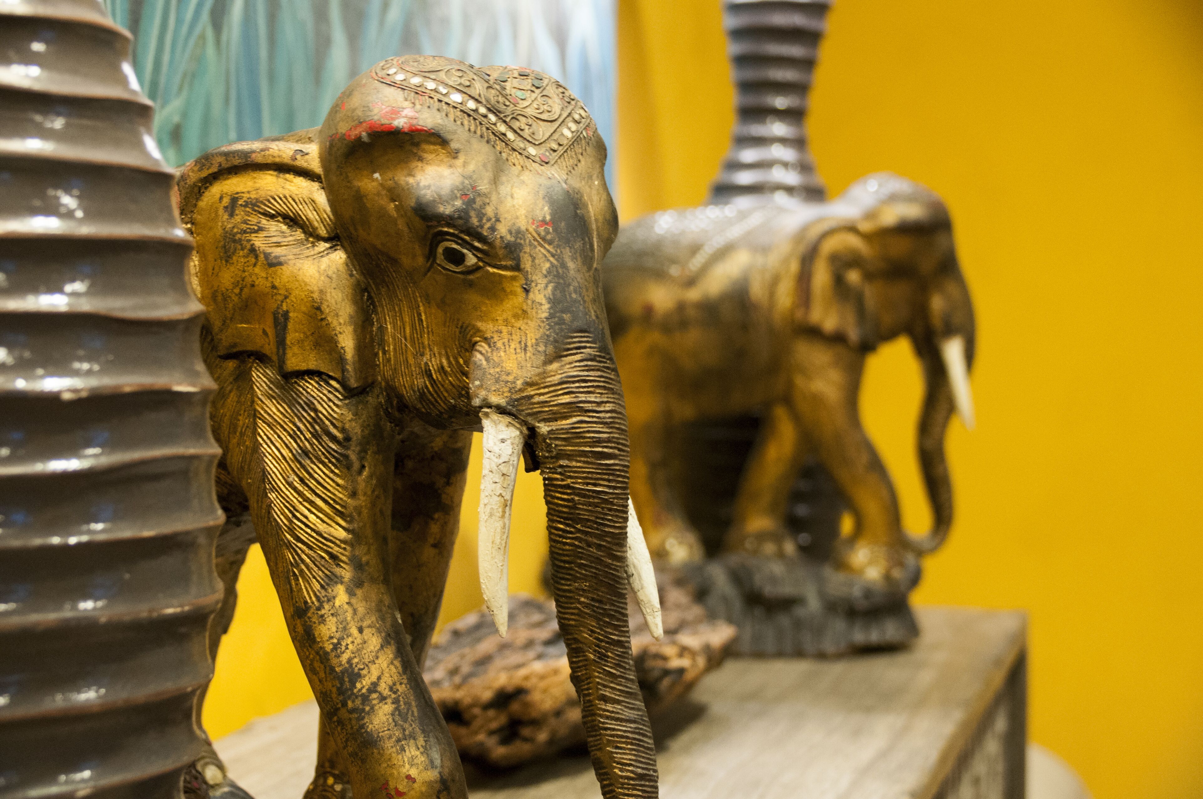 A close-up of a wooden elephant sculpture with intricate carvings and a decorative headpiece.