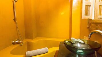 Un baño con un lavabo amarillo, una pila de cristal y una ducha.