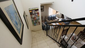A staircase leading to a living area with a sofa, a coffee table, and a bookshelf. - Tesorino (Umhlanga)