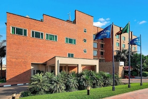 A brick building with multiple windows, a covered entrance, and flags.