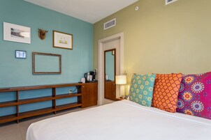 Una habitación de hotel con cama, un banco de madera, una cafetera y un espejo.