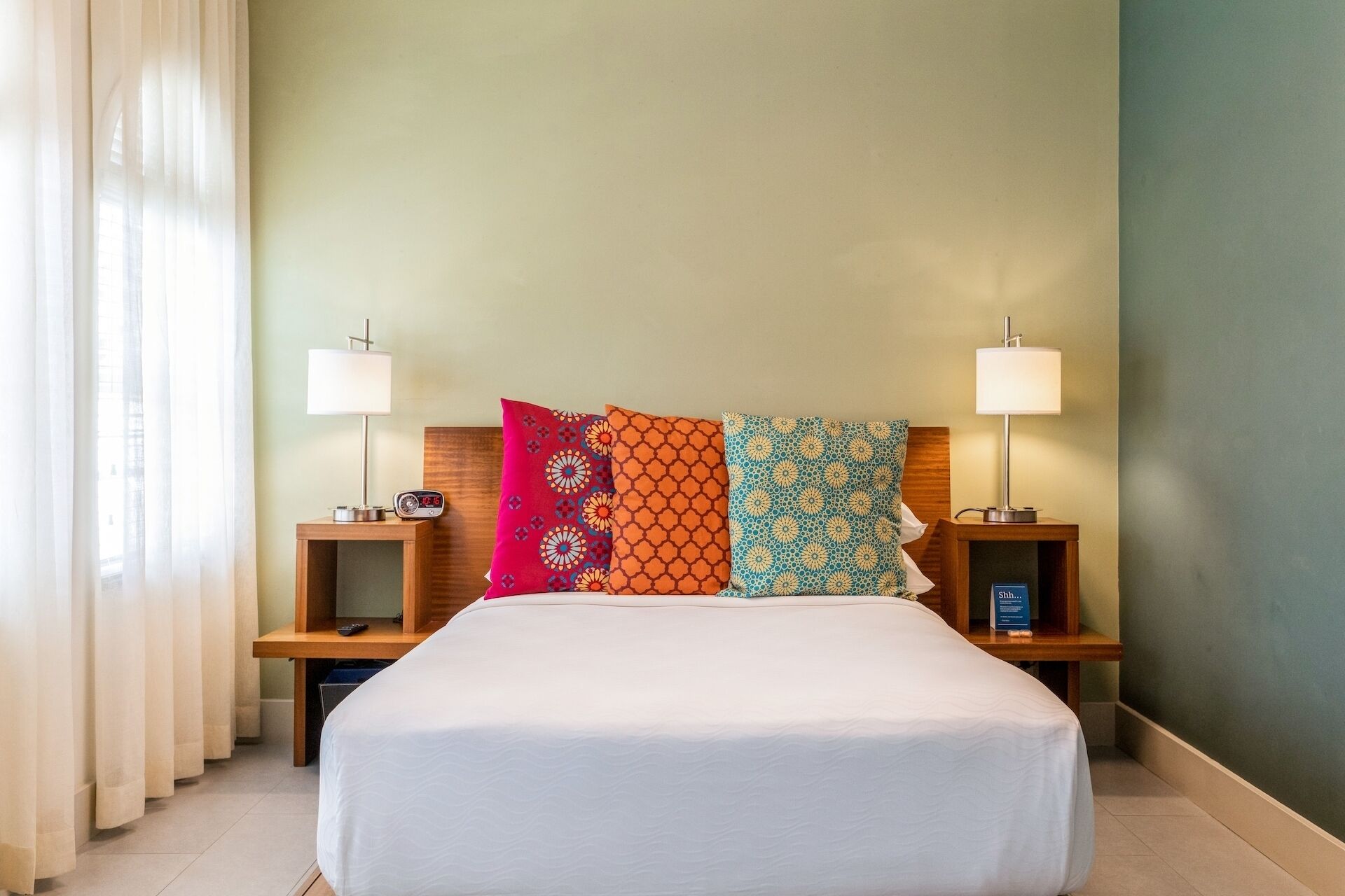 A hotel room with a large bed, two bedside tables with lamps, and three decorative pillows.