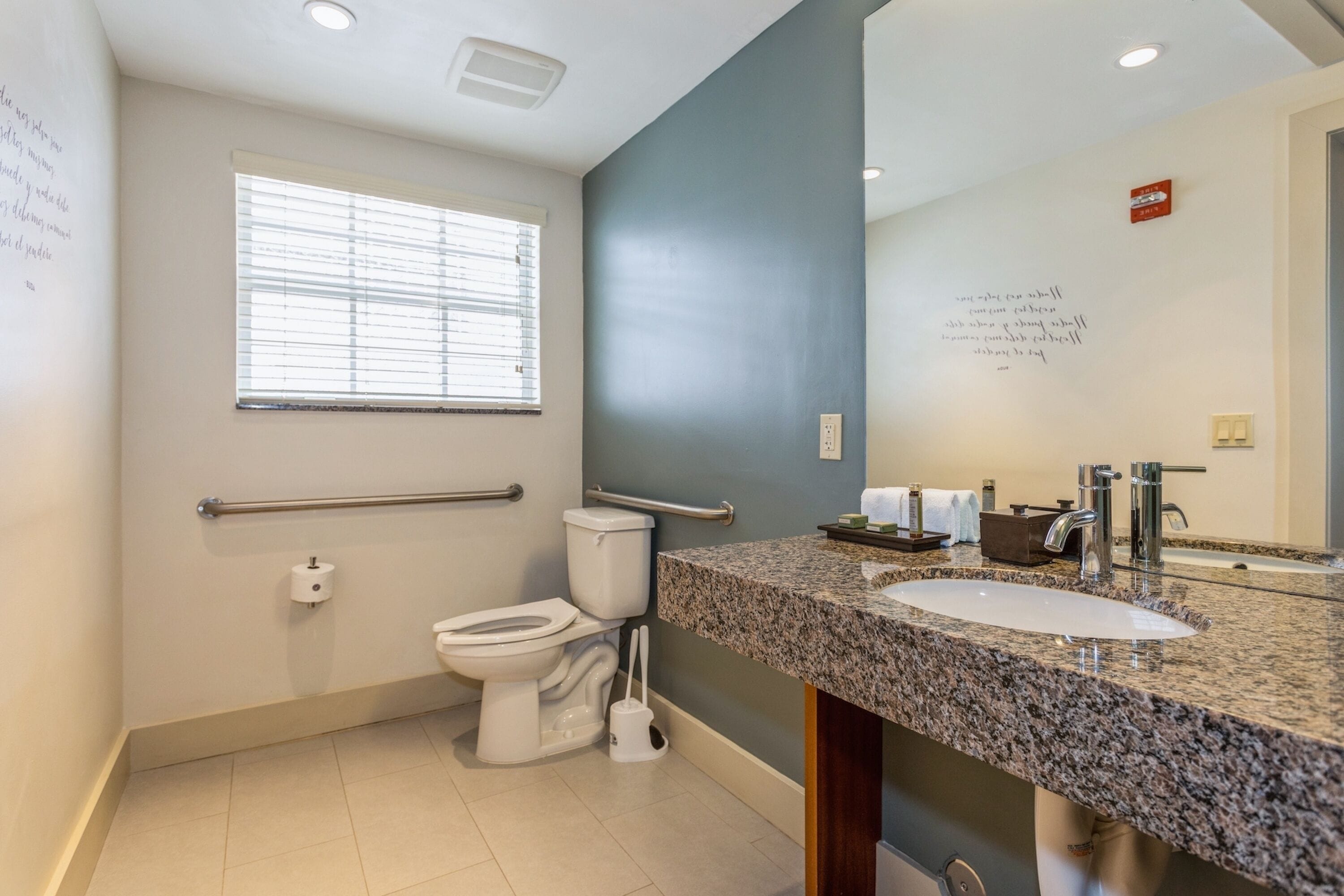 A modern bathroom with a toilet, sink, and window.