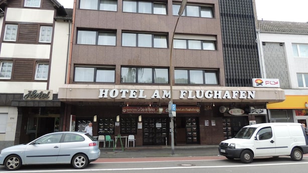 A hotel with a sign reading 'HOTEL AM FLUGHAFFEN' and a visible entrance with a car parked in front. - AM Flughafen (KOLN)