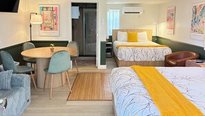 Una habitación de hotel con cama, escritorio, silla, sofá y mesa de comedor.