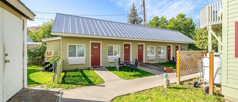 A single-story building with a metal roof, a front porch, and a small outdoor seating area.
