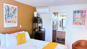Una habitación de hotel con una cama, un escritorio con una computadora, aire acondicionado, un baño con espejo y dos cuadros de Henri Matisse.