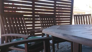 A patio area with a wooden table and chairs, a patterned cushion, and a wooden fence. - Bororen Motel (Bororen)