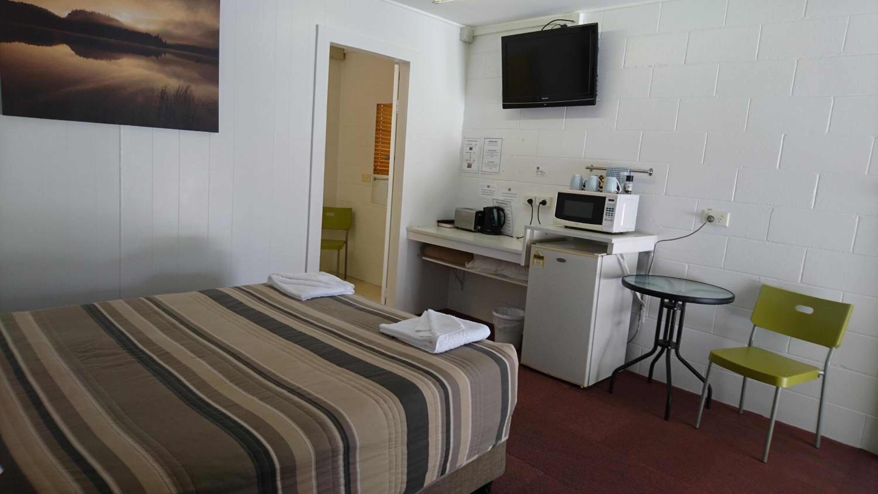 Habitación de hotel con cama, kitchenette pequeña, televisión y vistas al exterior.