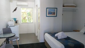 A hotel room with a bed, a desk, a chair, a ceiling fan, a window, and a picture on the wall. - Bororen Motel (Bororen)