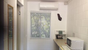 A small kitchenette with a microwave, a window with blinds, and a towel hanging on a rack. - Bororen Motel (Bororen)