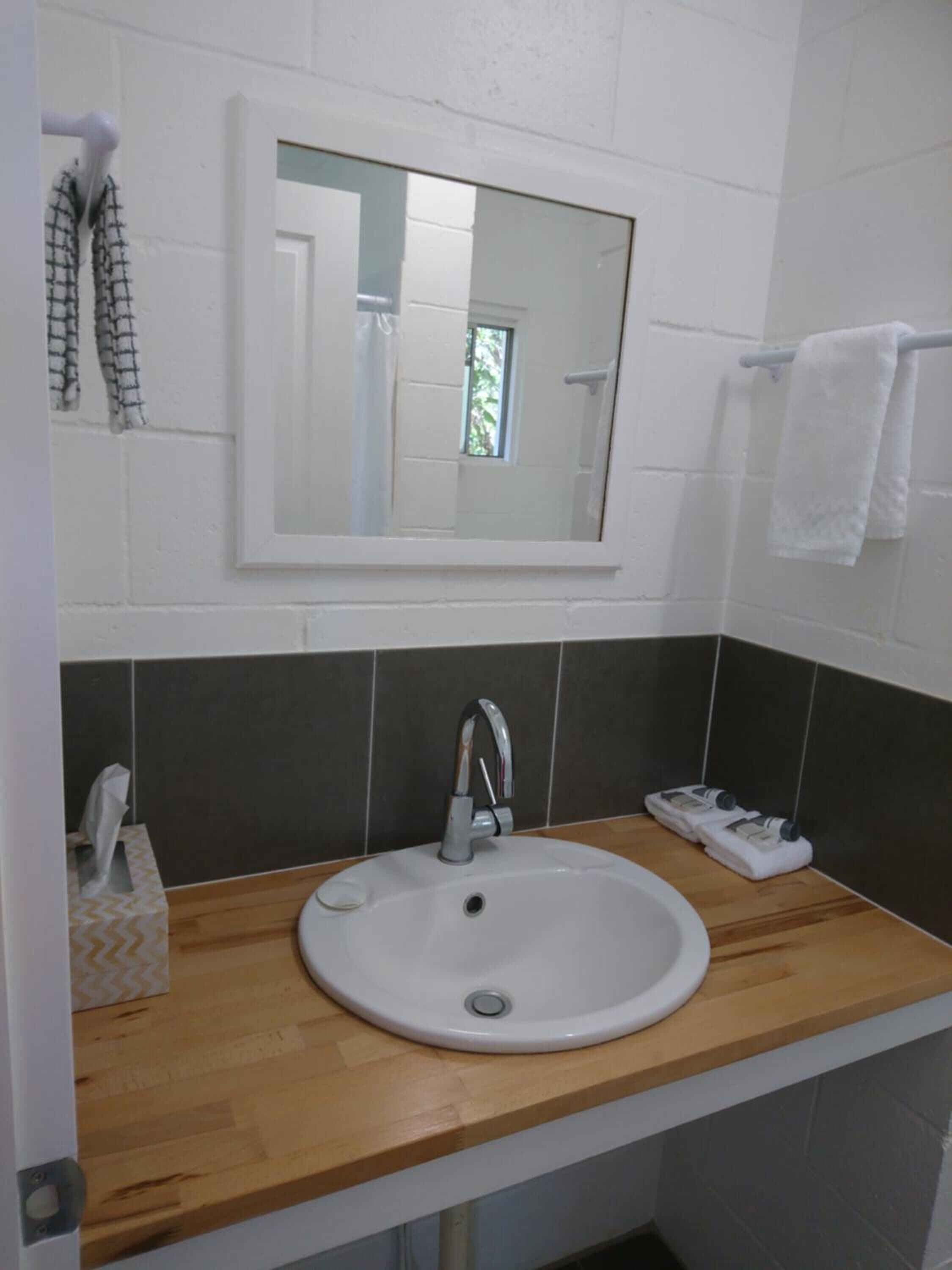 A bathroom with a white sink, a mirror above it, and a towel rack to the right.
