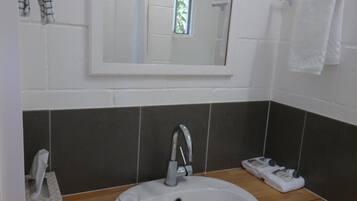 A bathroom with a white sink, a mirror above it, and a towel rack to the right.