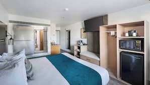 A hotel room with a bed, a microwave, a refrigerator, a TV, and a small kitchenette area. - The Marina Inn (Anacortes)