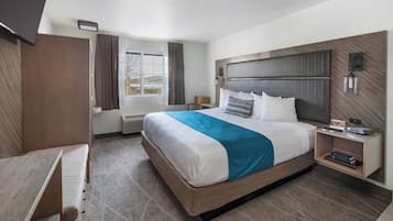 Una habitación de hotel moderna con una cama grande, un escritorio, una silla y una pequeña mesa.