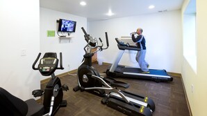 A gym with a treadmill, elliptical, and stationary bike. - The Marina Inn (Anacortes)