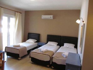 Une chambre d’hôtel avec deux lits simples, une petite table, une chaise et un bureau.